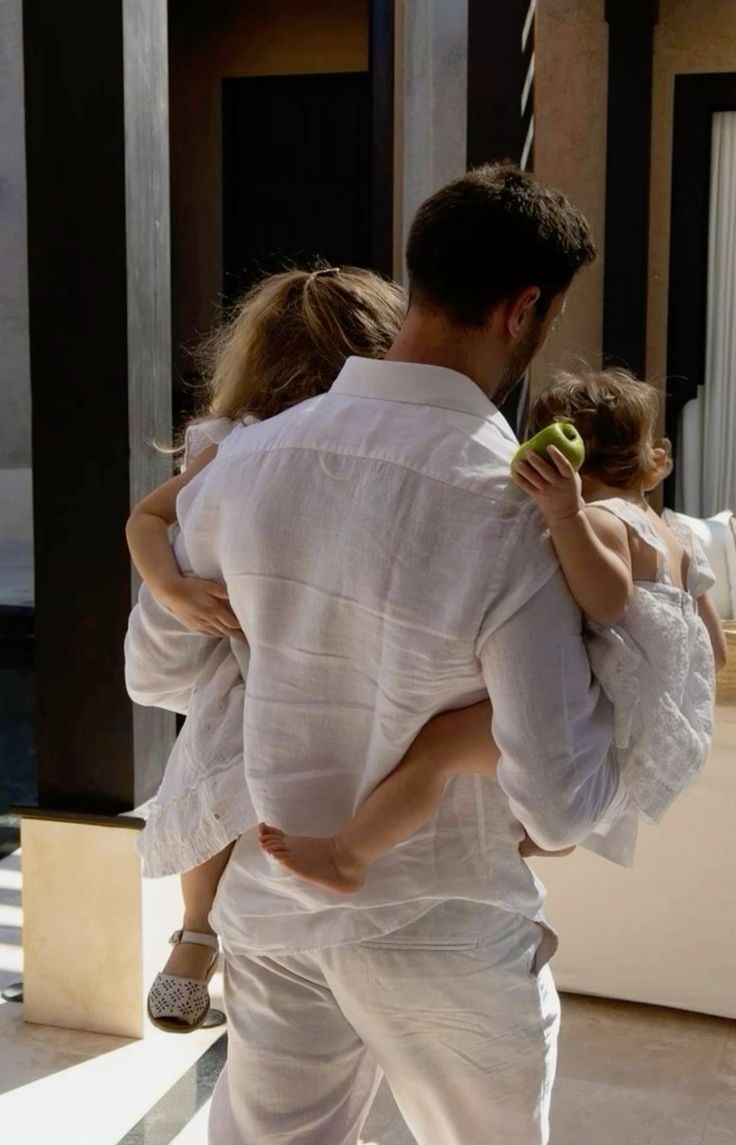 Un parent porte deux enfants dans une lumière d'été